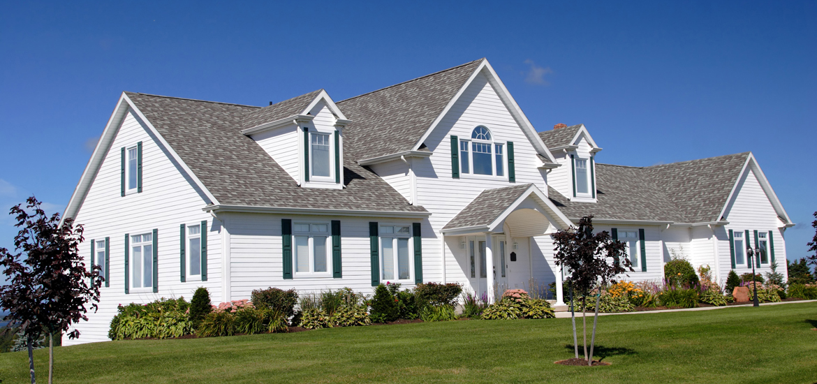 An upscale executive home surrounded by a lush green lawn.