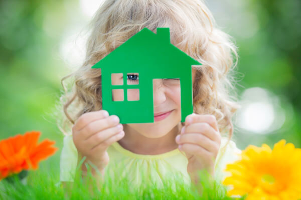 Girl looking through paper cut out of house